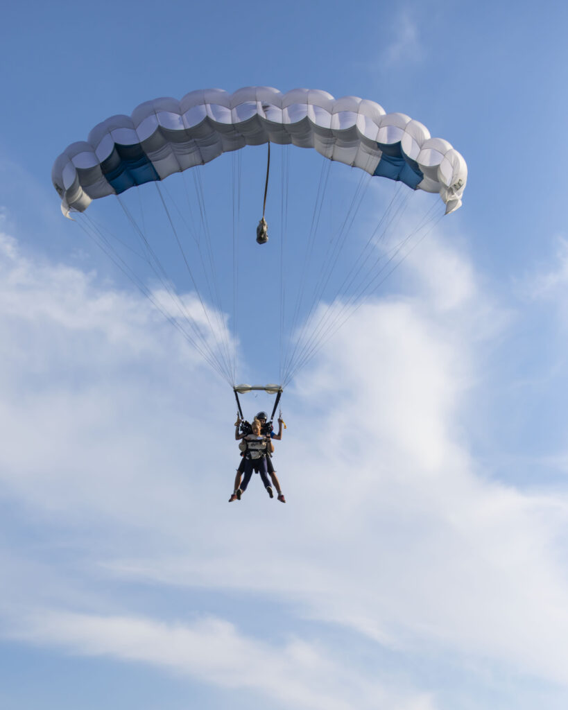 tandem first jump pair descends under canopy at skydive chicago